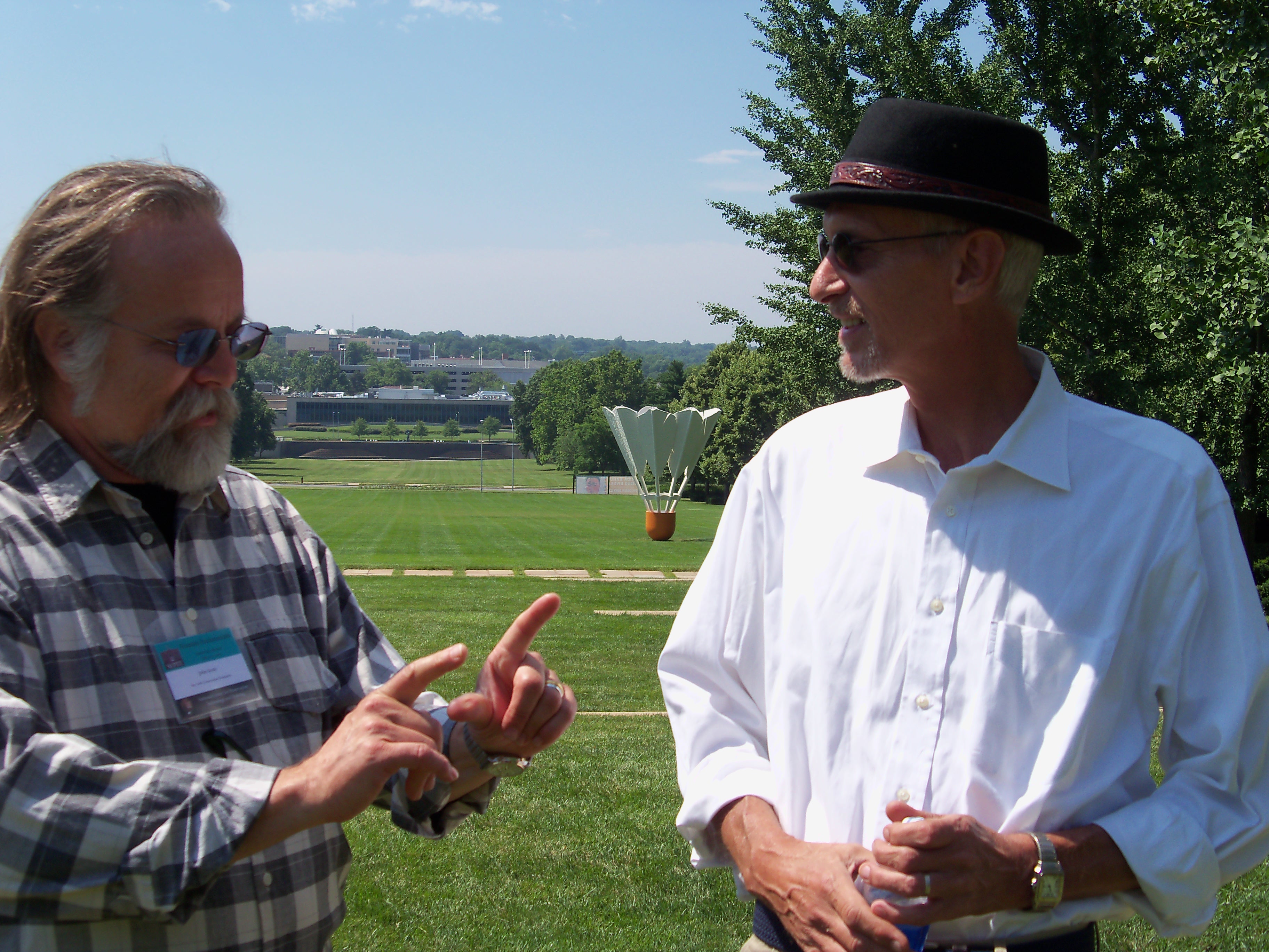 Photo of John Scott talking with Kirk Auston in summer of 2013 on the lawn in front of the Nelson-Atkins Museum